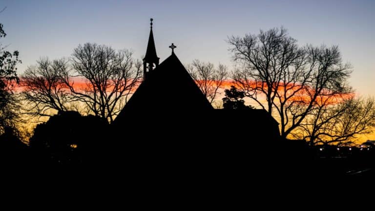 Silhouette of church against vibrant sunset.