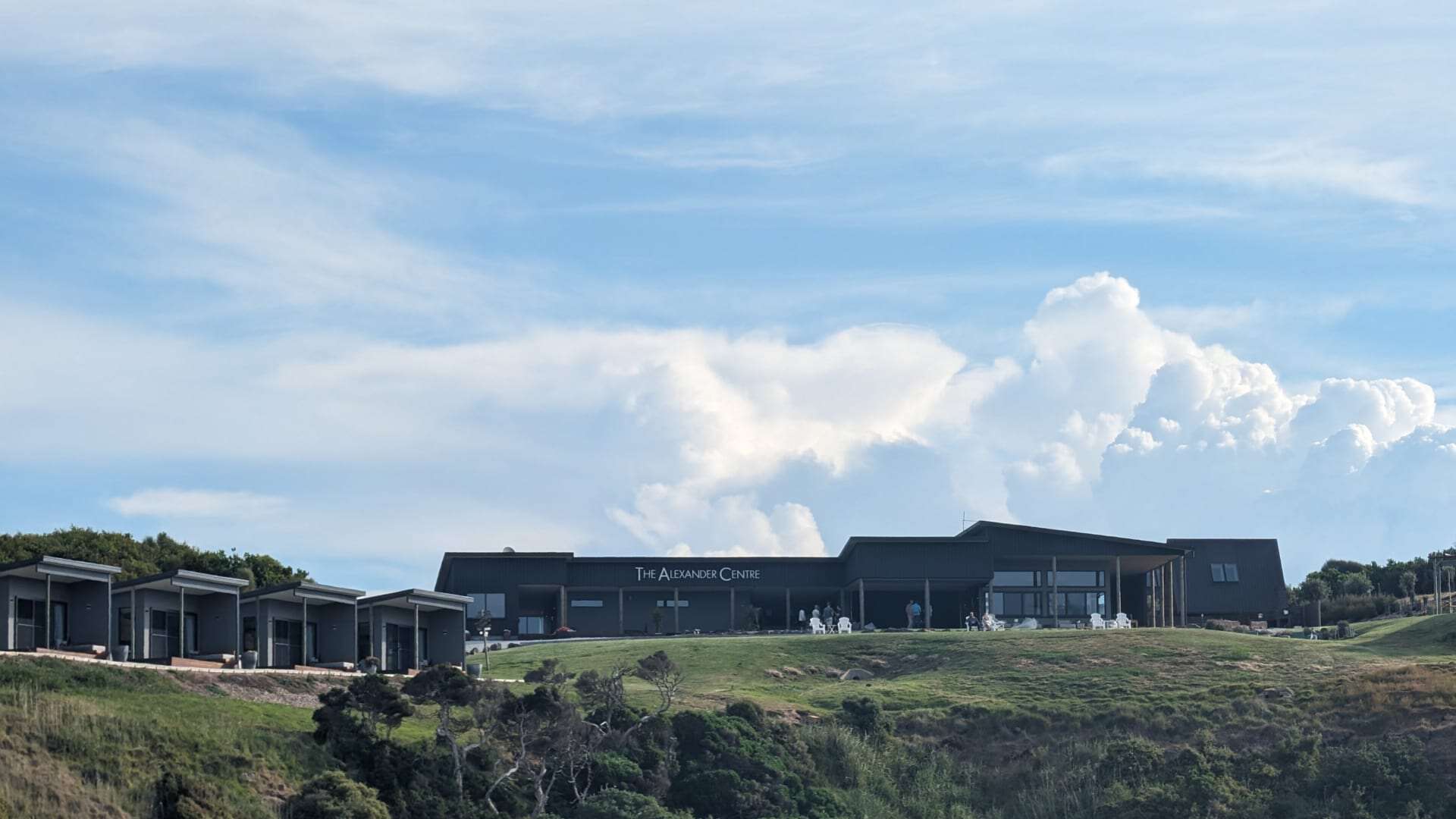 Modern facility on grassy hill under cloudy sky