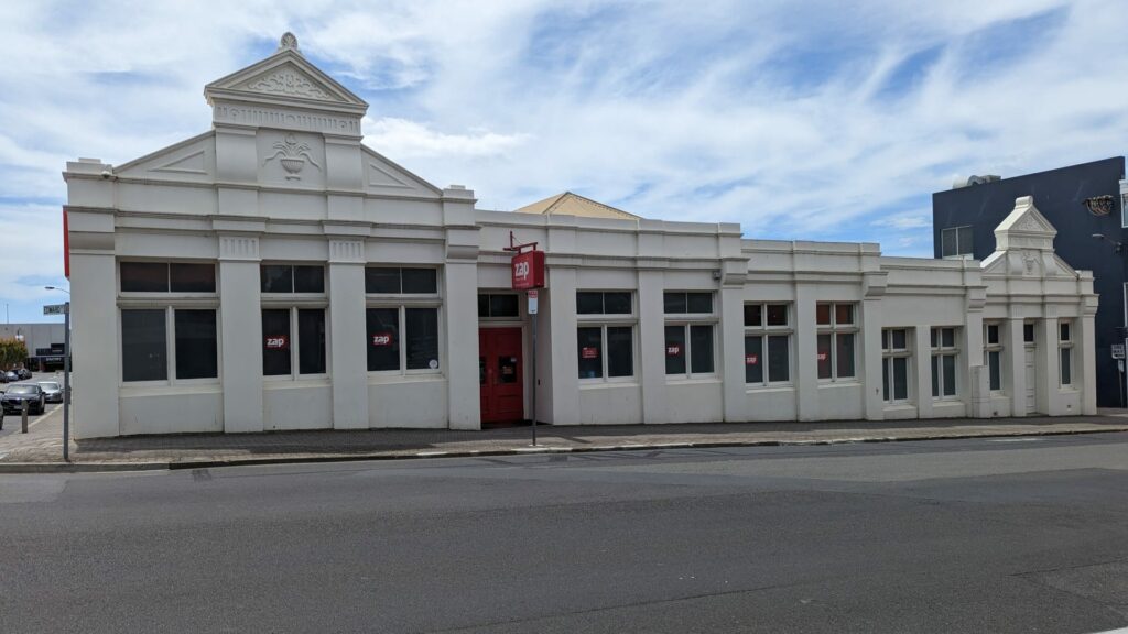 Historic Australian building with red door and signage.