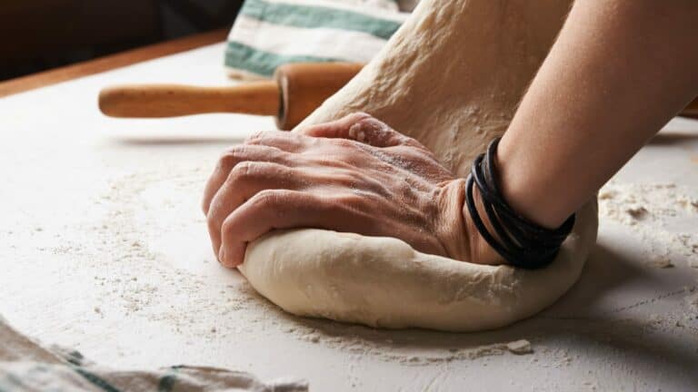 Kneading dough on kitchen bench with rolling pin