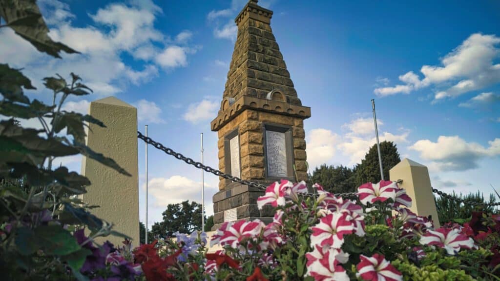 Historic war memorial surrounded by colorful flowers.