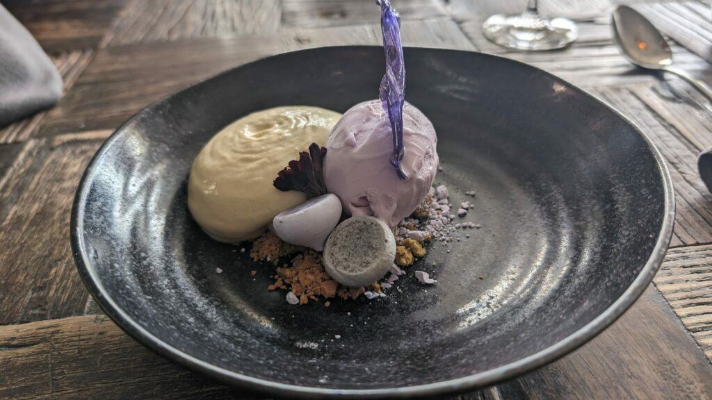 Gourmet lavender dessert on black plate.